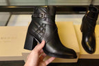 Black leather ankle boots with quilted panels and buckle strap