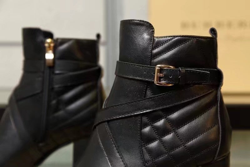 Close-up of black leather ankle boot strap with gold buckle