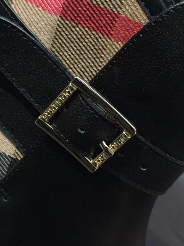 Black boot strap buckle with gold-tone hardware over plaid interior lining