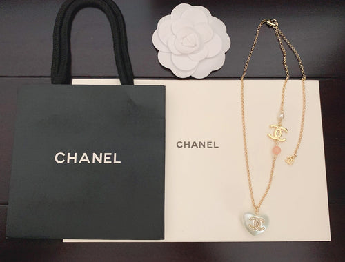Gold-tone layered necklace with heart and charm pendants, Chanel logo, pink bead