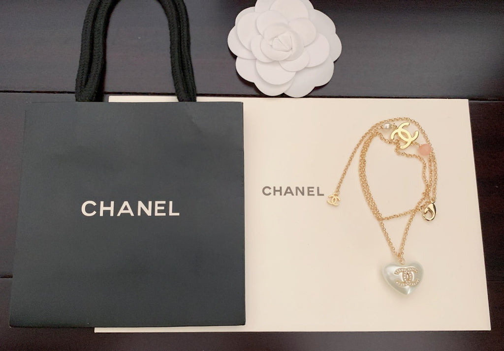 Gold-tone necklace with heart pendant and Chanel logo charm, pink bead