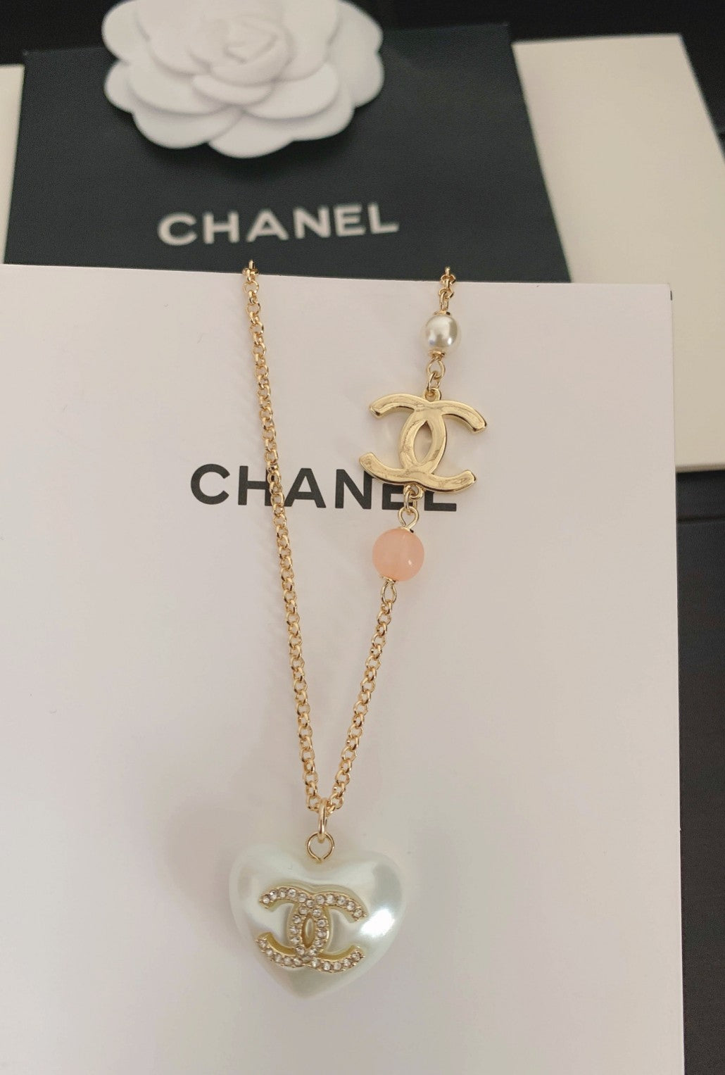 Gold-tone heart pendant necklace with pink bead and Chanel logo charm