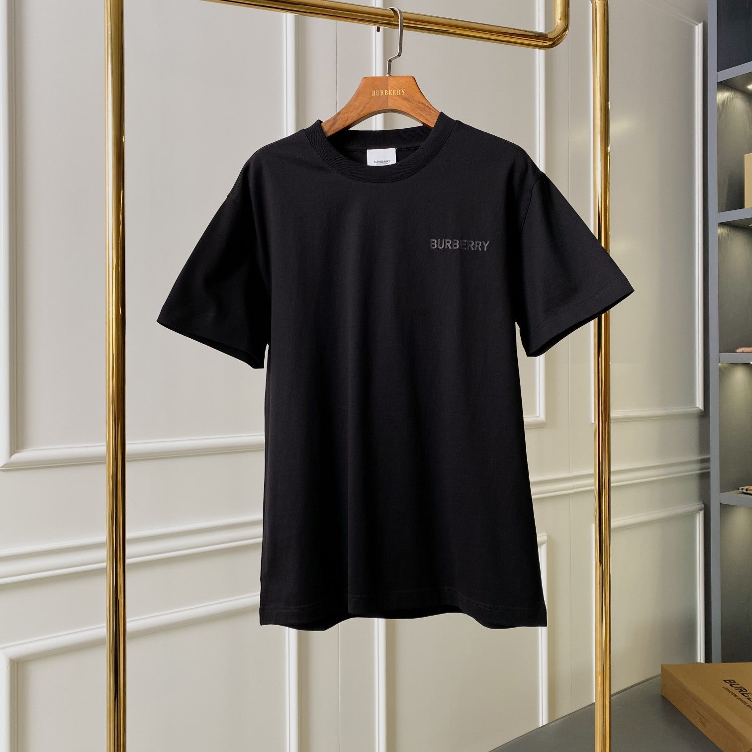Black short-sleeve T-shirt on a hanger with subtle chest logo print