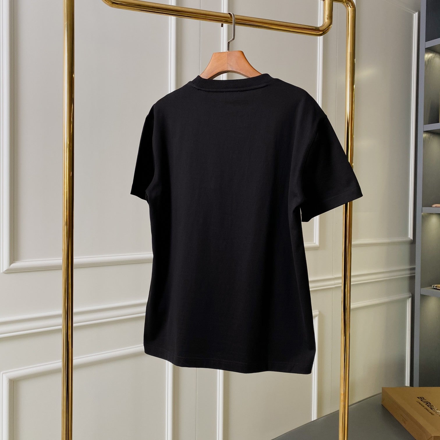 Black short-sleeve T-shirt shown from the back on a hanger