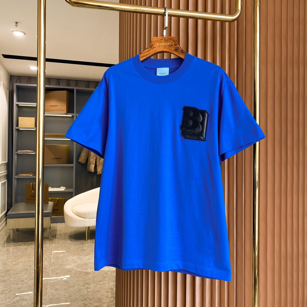 Men's blue short-sleeve T-shirt with black B logo patch at chest.