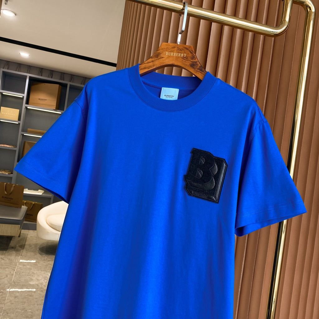 Men's blue T-shirt with crew neck and black B logo patch on chest.