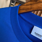 Blue T-shirt neckline detail with ribbed collar and Burberry tag inside.