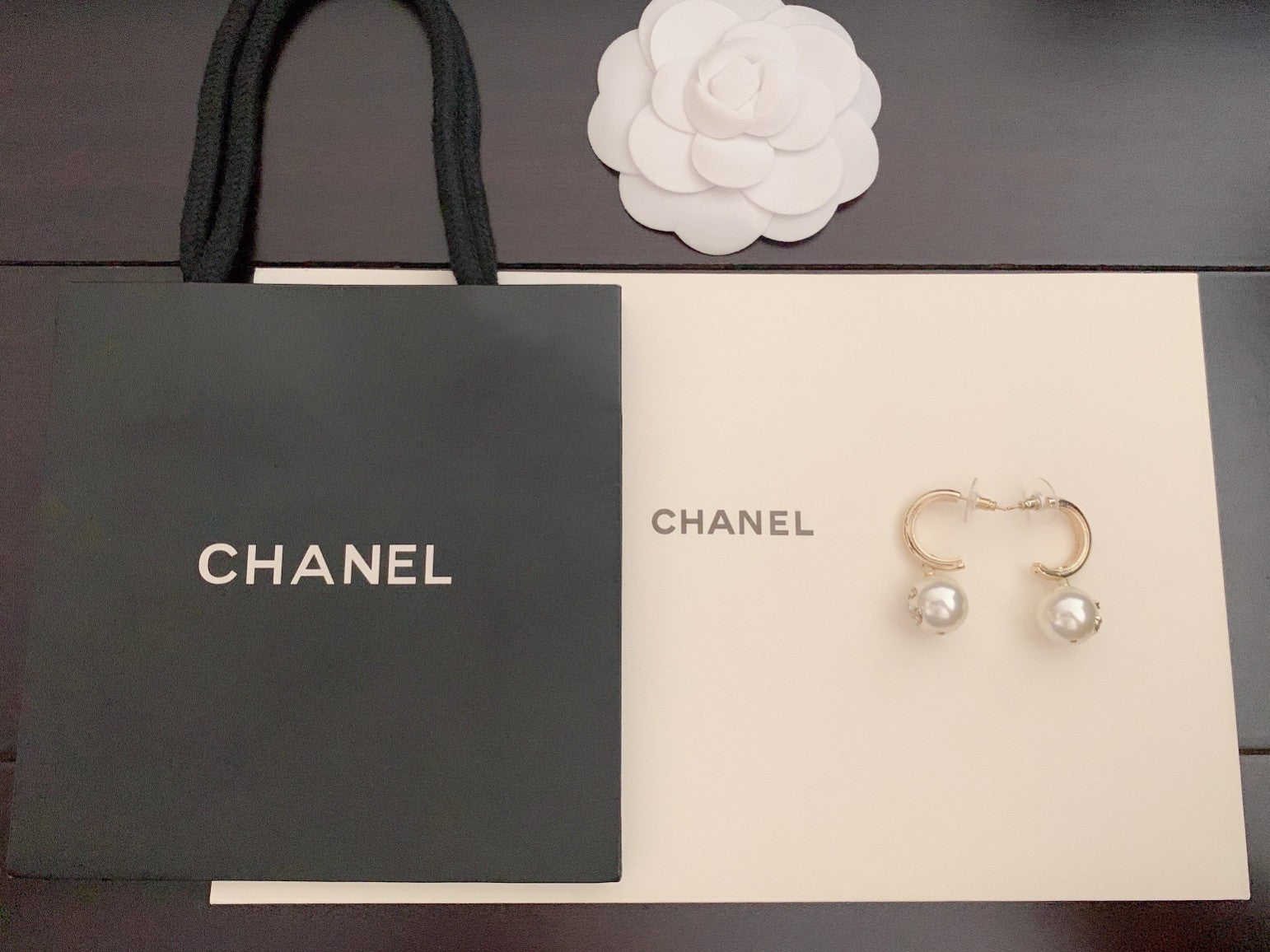 Gold-tone hoop earrings with pearl bead drops, shown with branded gift boxes
