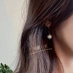 Round pearl-drop earrings on model with dark hair