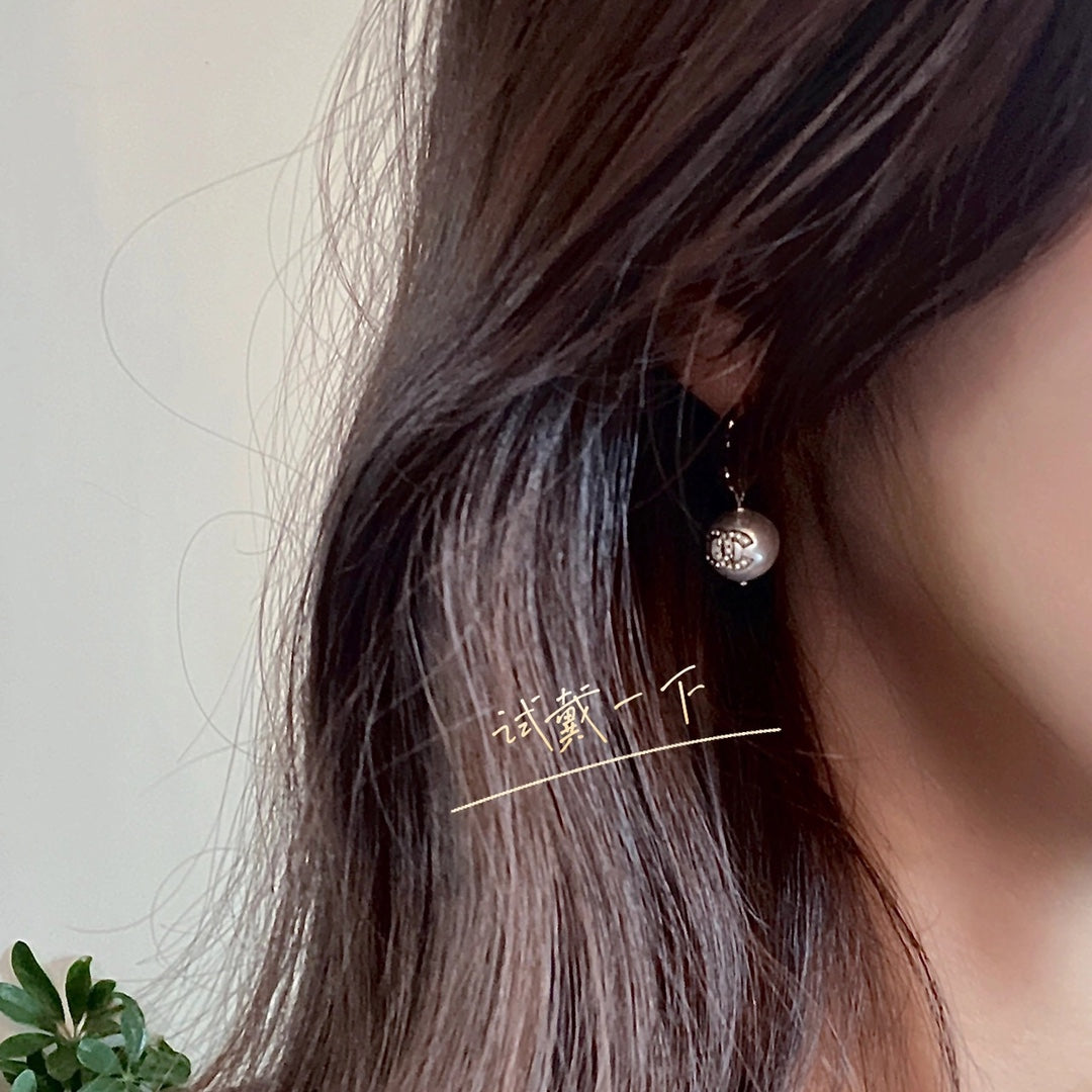 Round pearl-drop earrings on model with dark hair