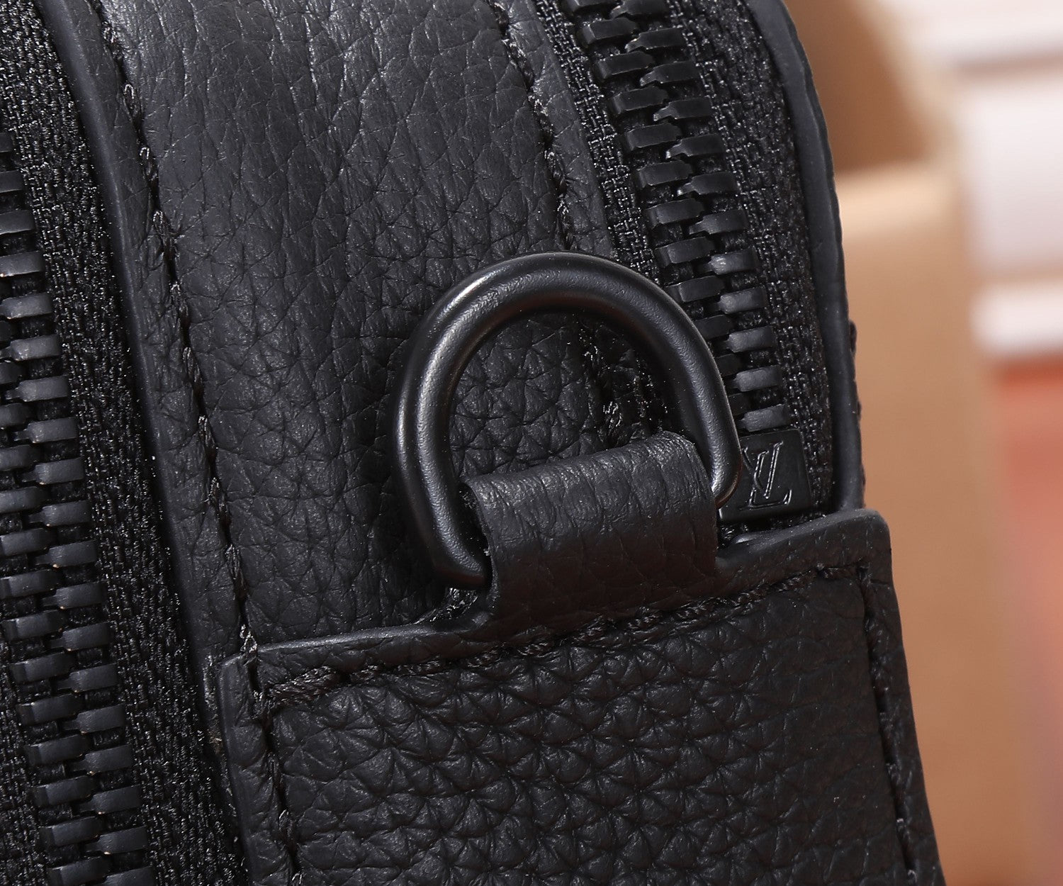 Black leather crossbody bag zipper pull with fabric tab and stitched edging
