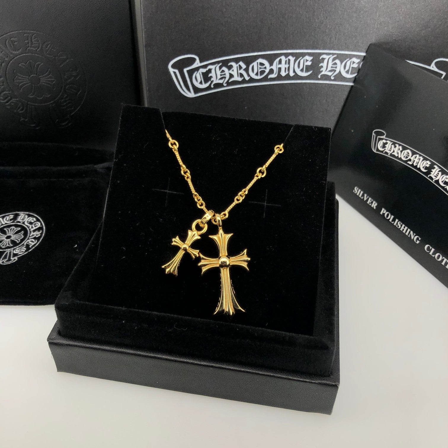 Gold cross pendant necklace displayed on black jewelry box