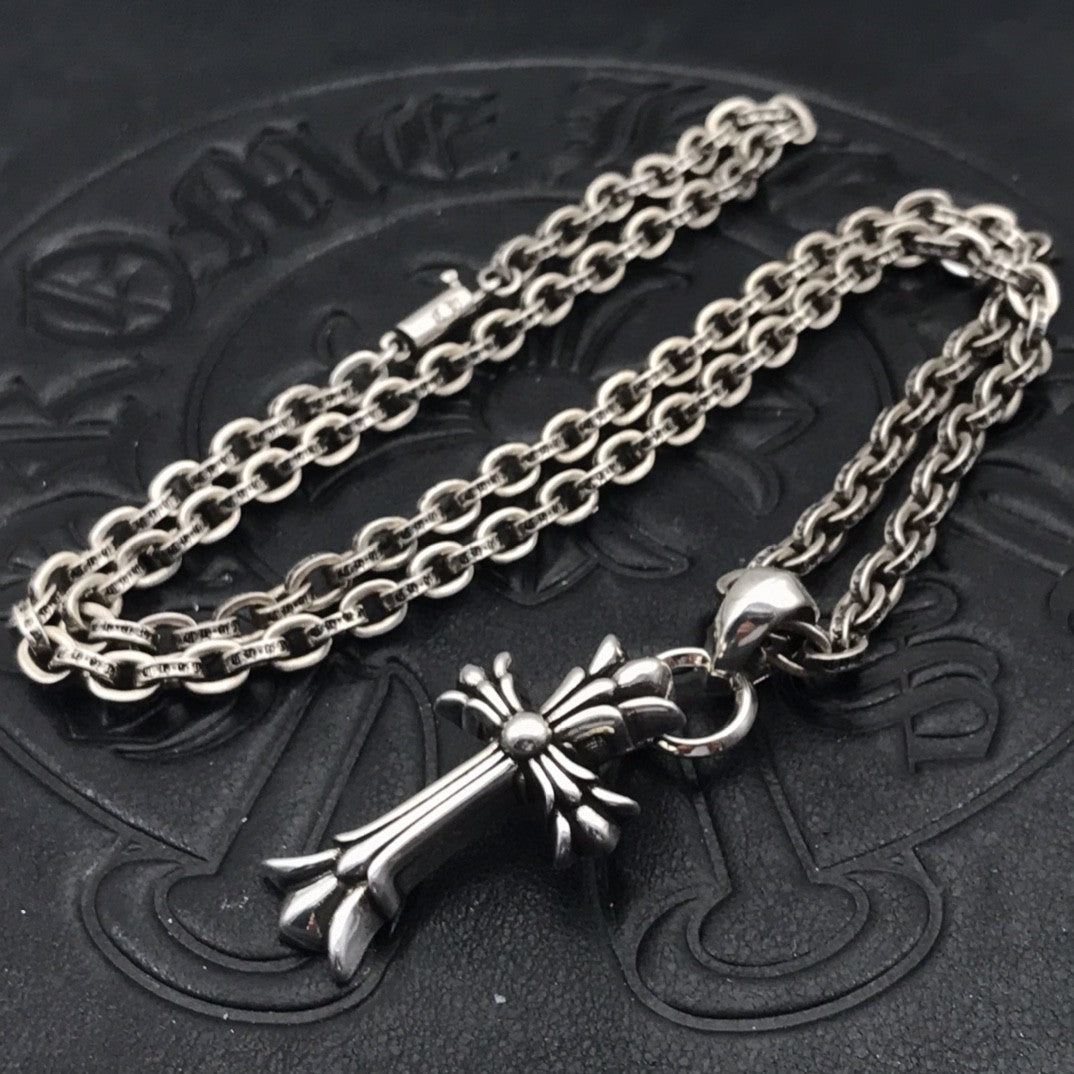 Silver-tone cross pendant necklace with decorative centerpiece and curb chain links
