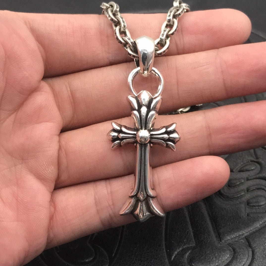 Silver-tone cross pendant necklace with ornate fleur-de-lis design on chain