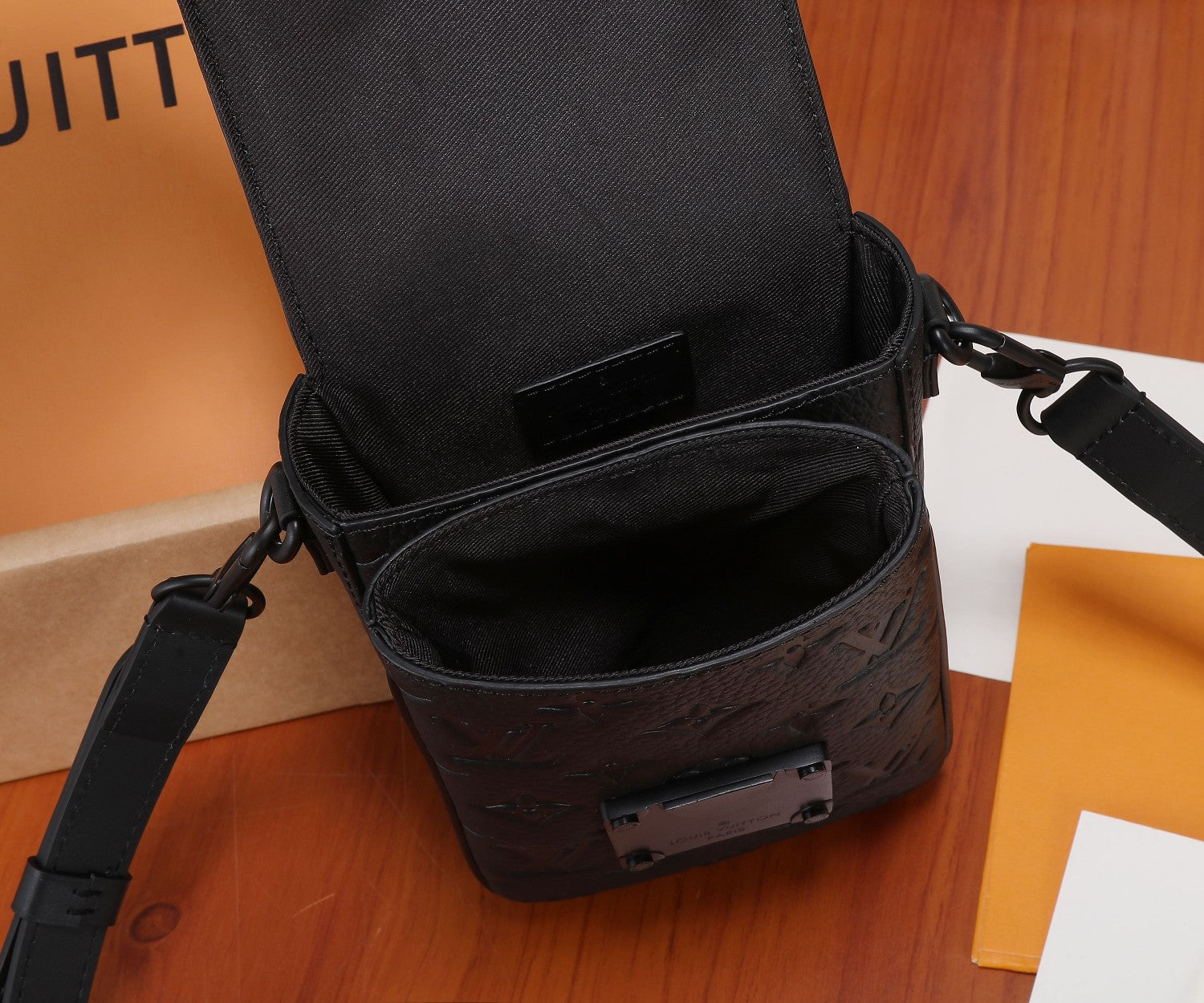 Black monogram crossbody bag open showing interior and front buckle detail