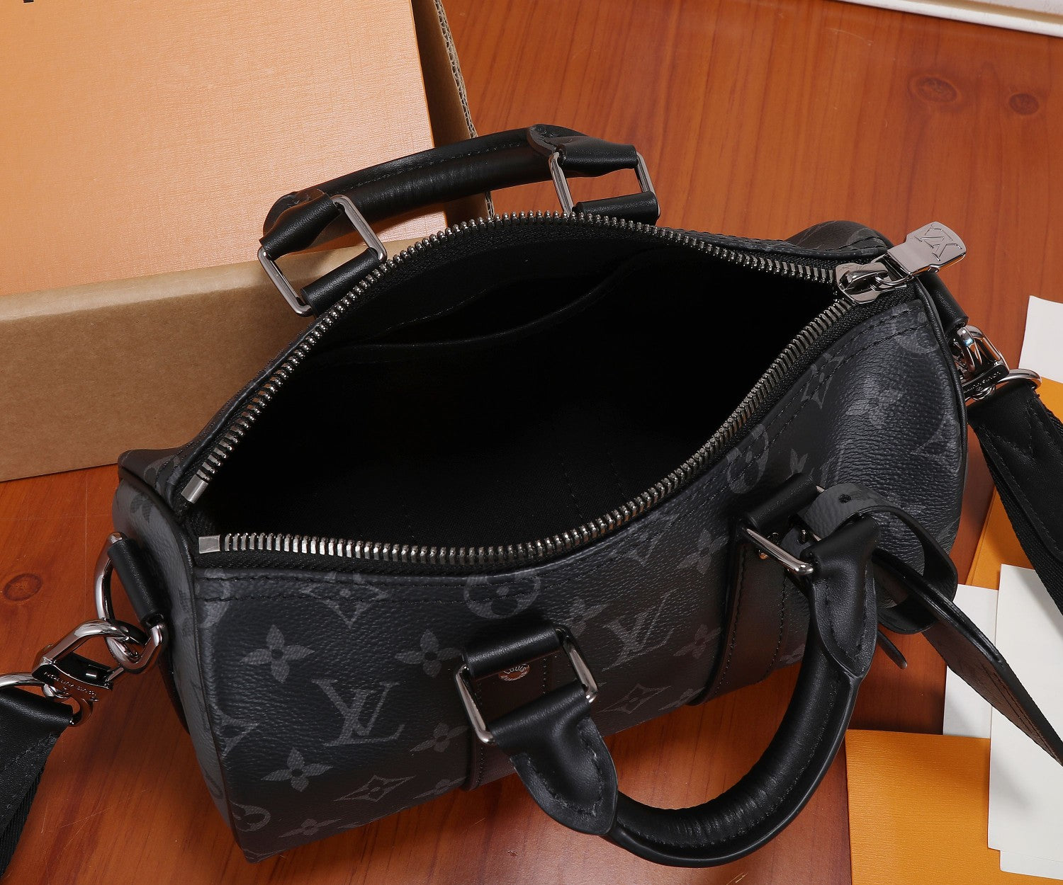 Louis Vuitton monogram bag open top with black interior and metal zipper at edge.