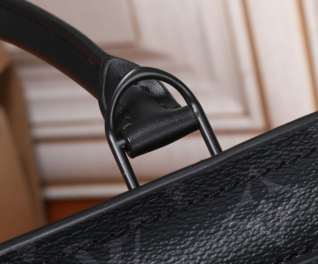 Black leather tote bag top handle with metal rings and textured grain