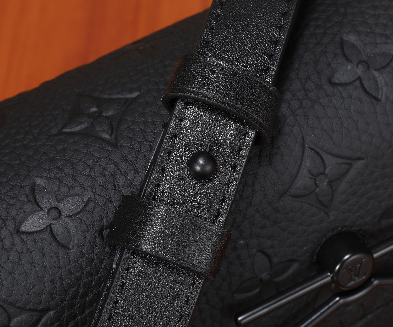 Black monogram crossbody bag strap attachment with leather tab and snap button