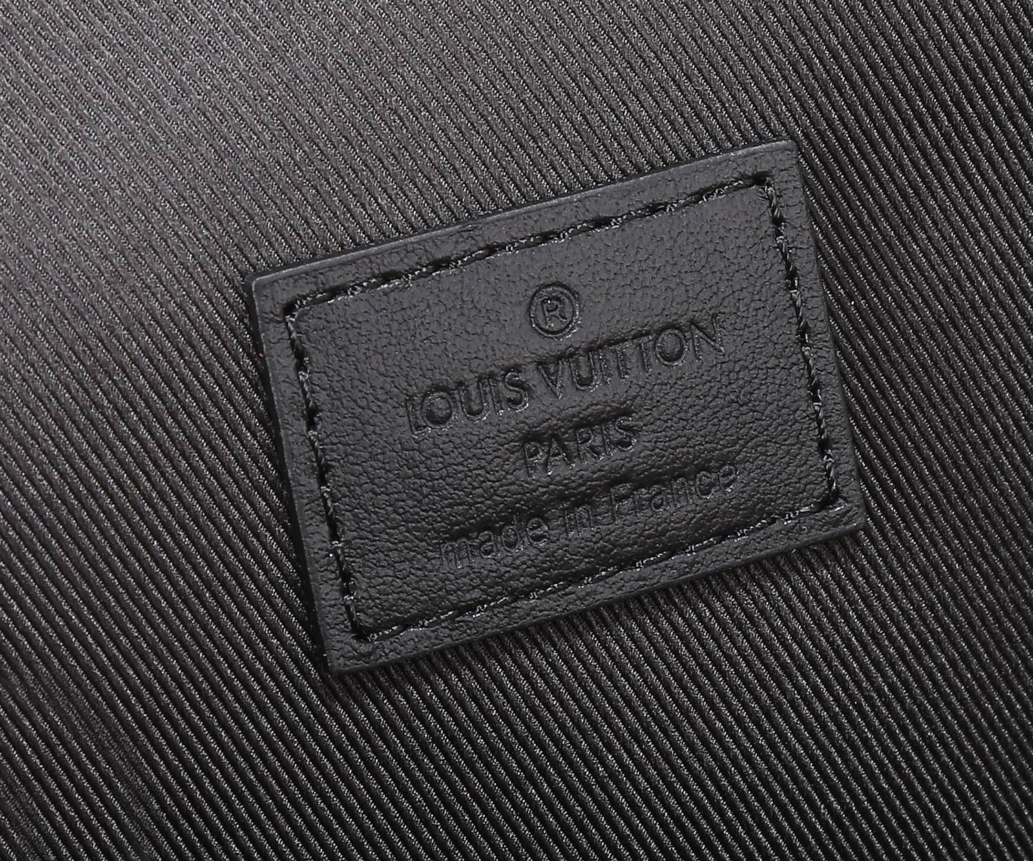 Leather brand patch on crossbody bag in black with embossed logo text