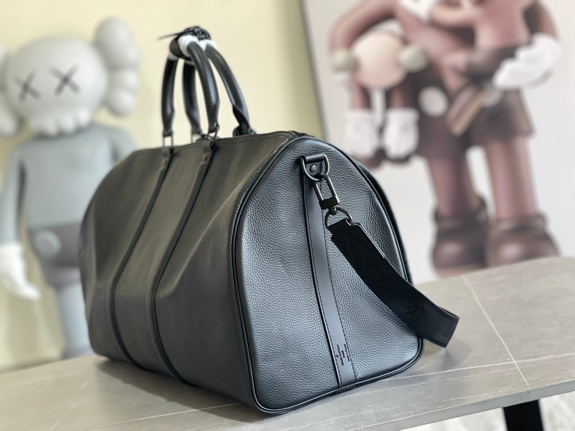 Leather duffle bag in dark blue with curved top handles and side wrist strap