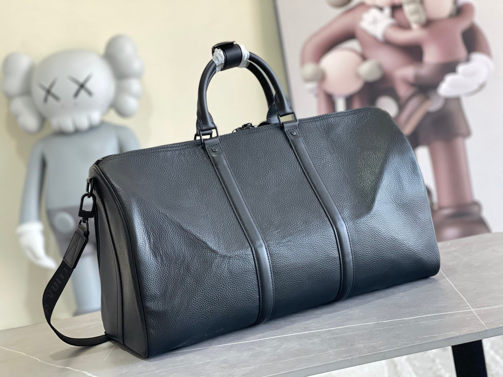 Leather duffle bag in dark blue with top handles, front zip pocket, and crossbody strap