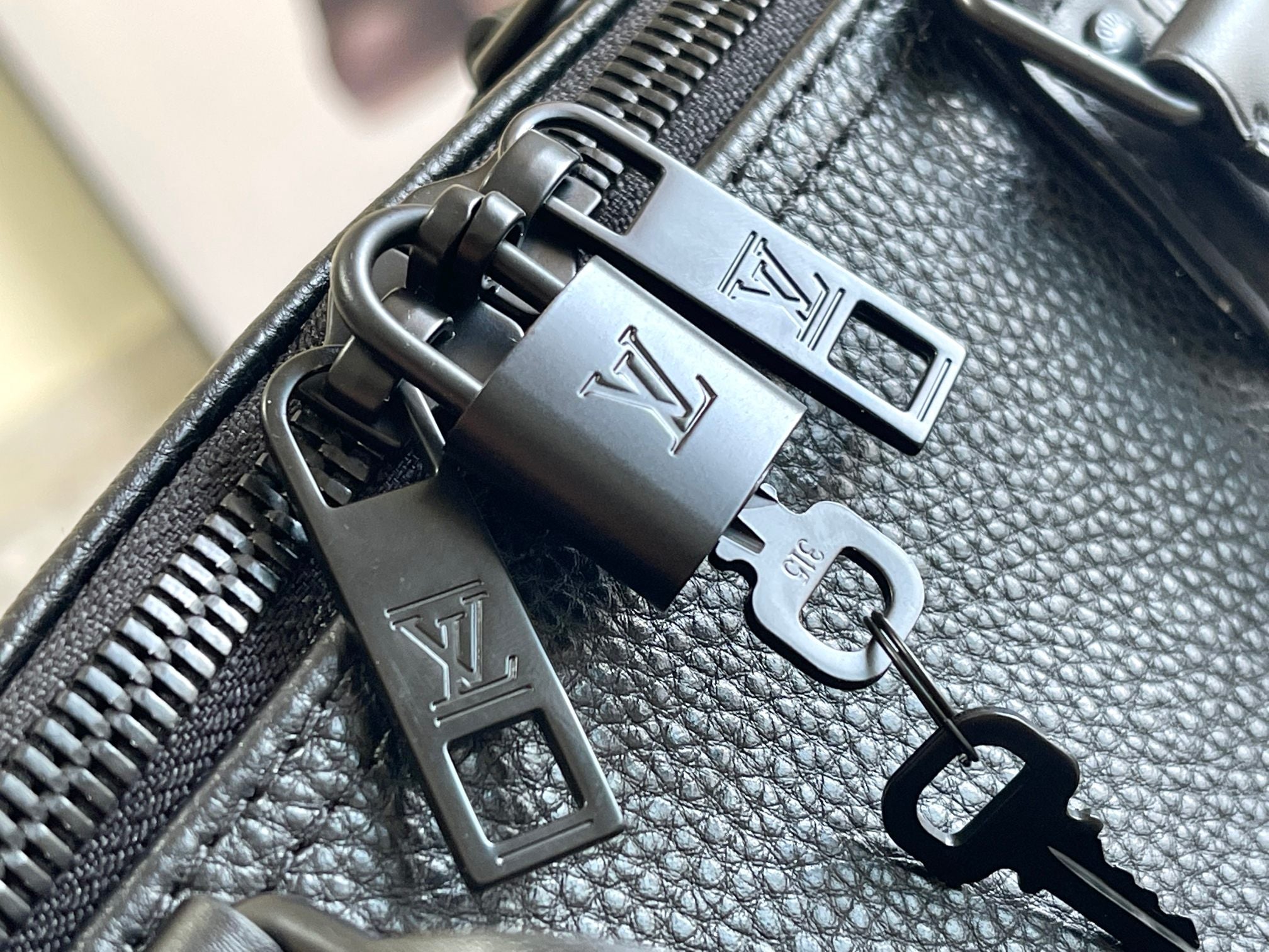 Leather bag hardware close-up with metal zipper pulls and LV-style accents