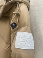 Tan puffer jacket close-up: Burberry London England logo patch and hanging pouch