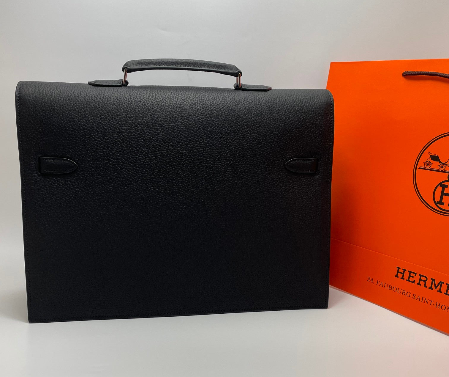 Black leather Hermes bag front view with dual side tabs and handle