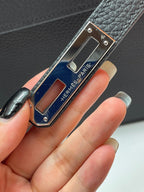 Hermes logo plaque on black leather bag with blue inlay and silver studs