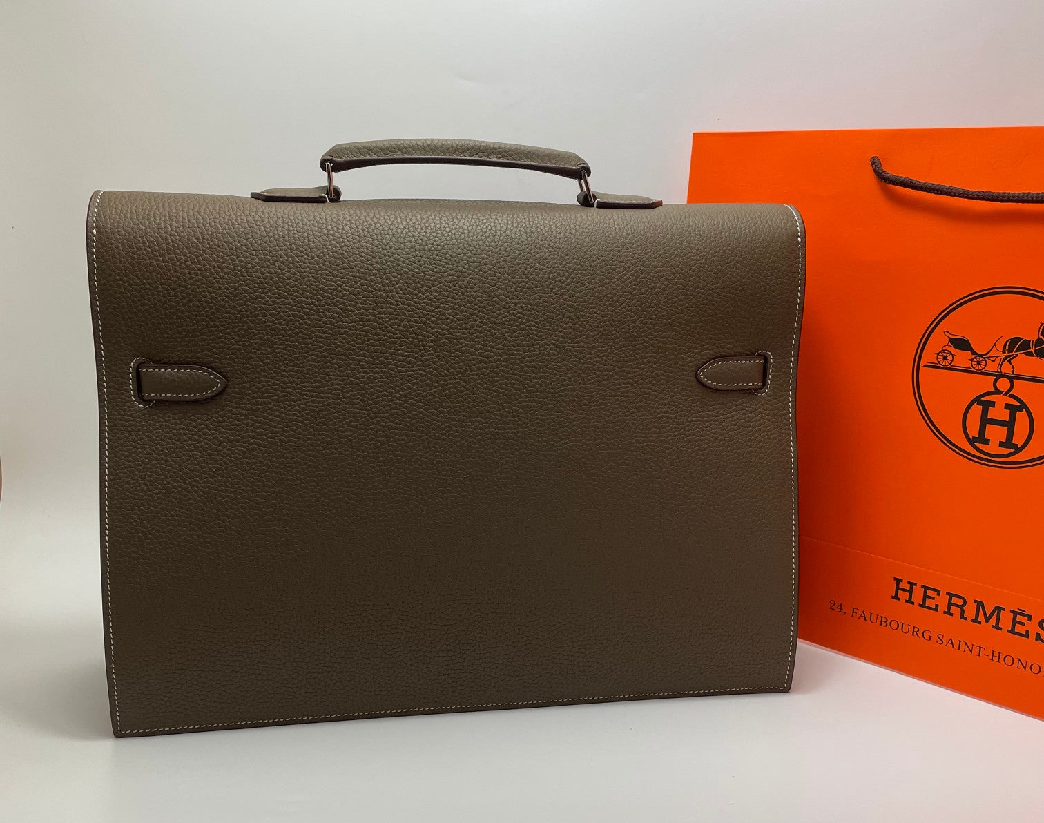 Taupe leather briefcase front view with two side buckle details and top handle