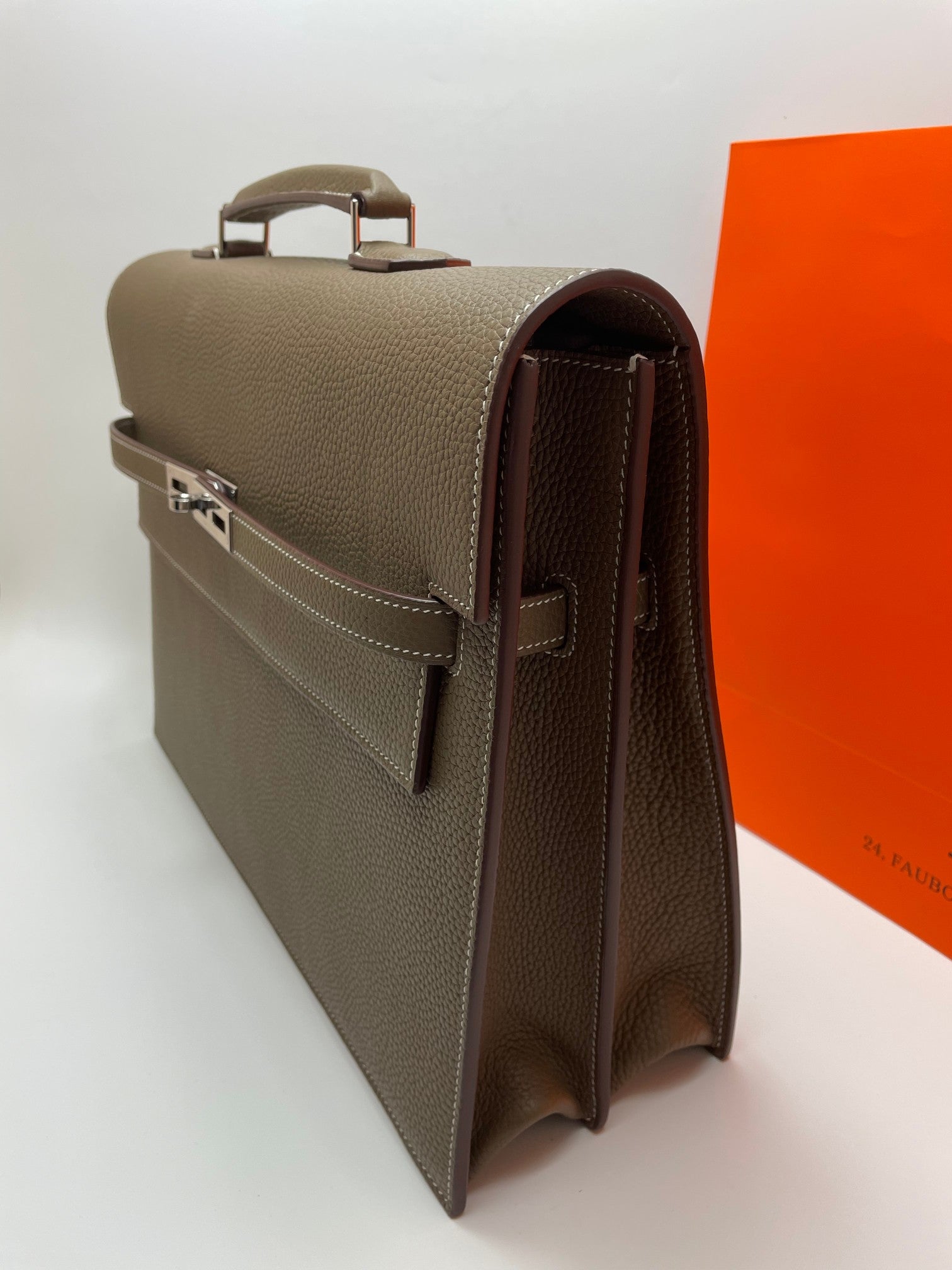 Taupe leather briefcase side profile with hinged clasp and rear handle strap