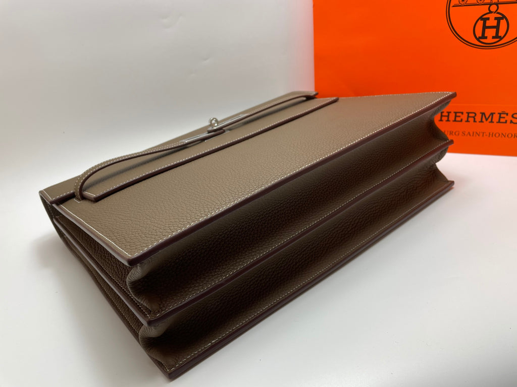 Taupe leather briefcase with long zipper track and foldover flap, flat lay
