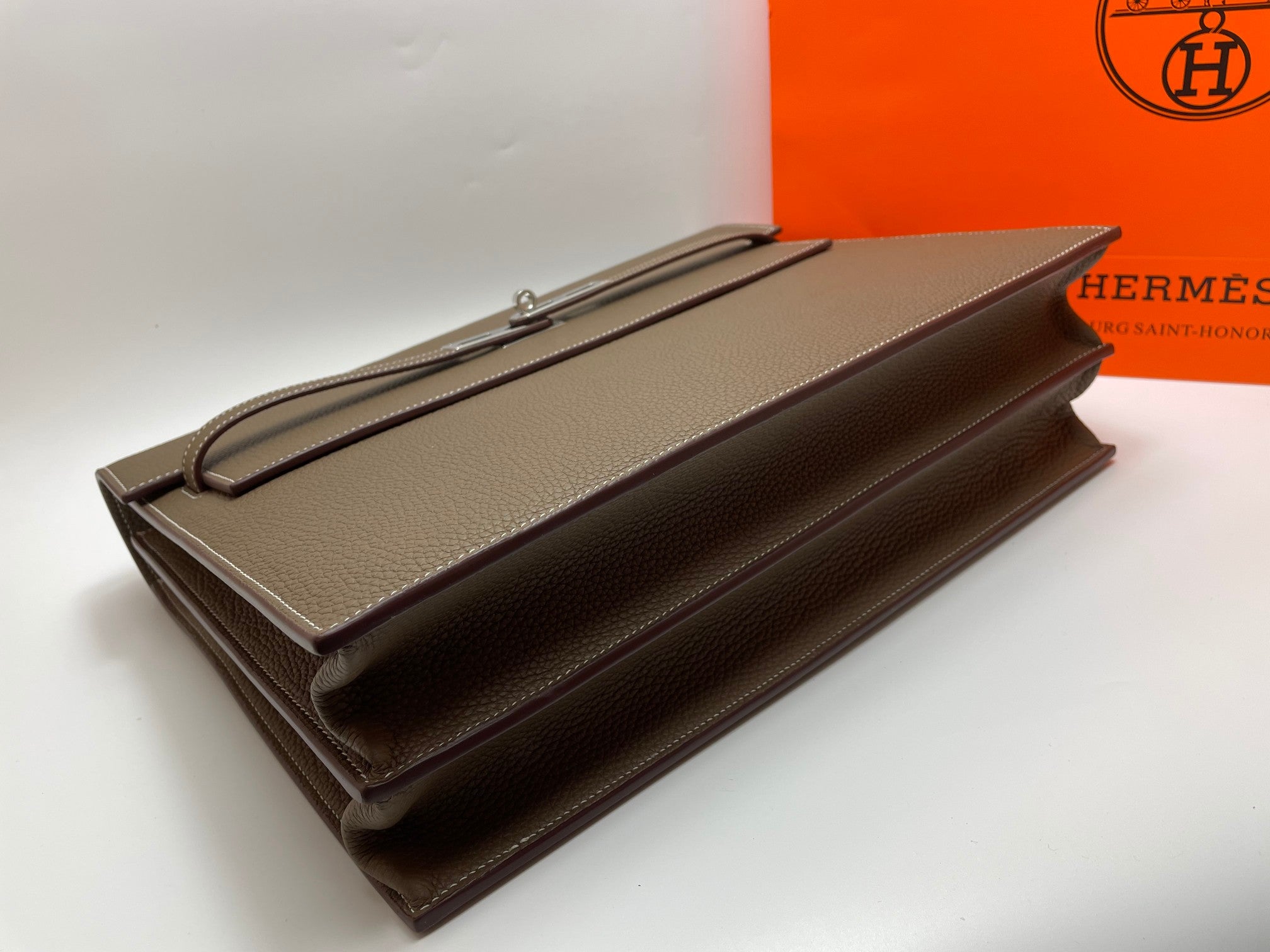 Taupe leather briefcase with long zipper track and foldover flap, flat lay
