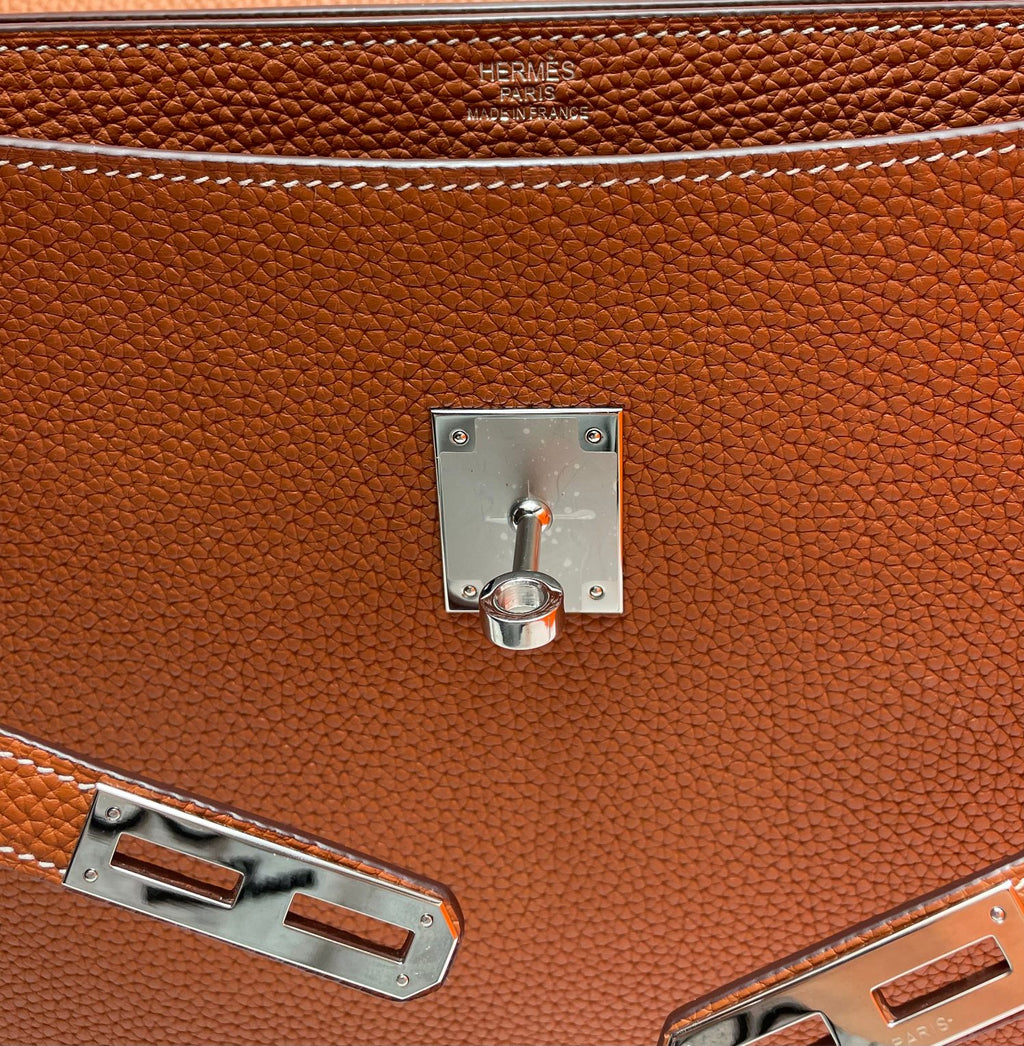 Hermes brown leather briefcase close-up of front lock, hardware, and stitching