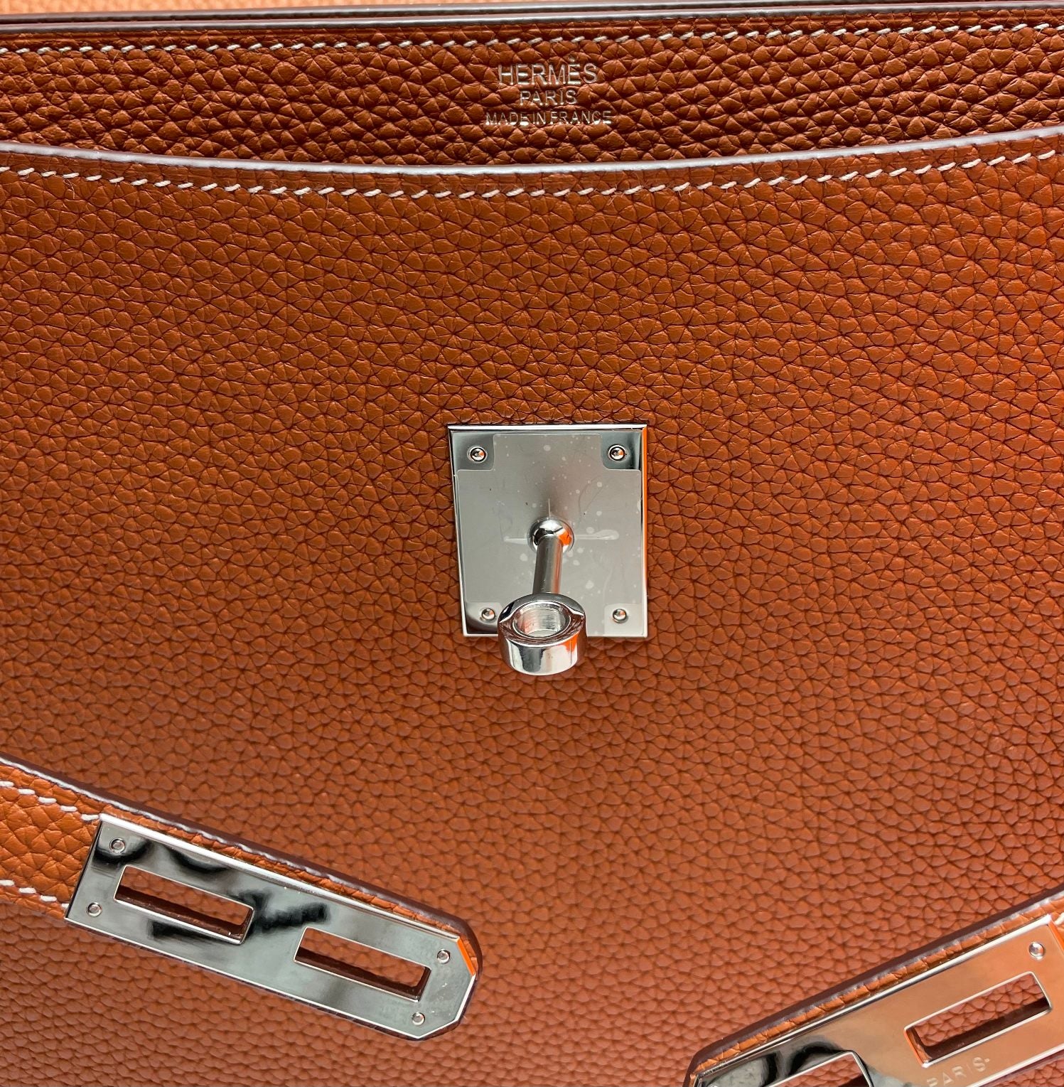 Hermes brown leather briefcase close-up of front lock, hardware, and stitching