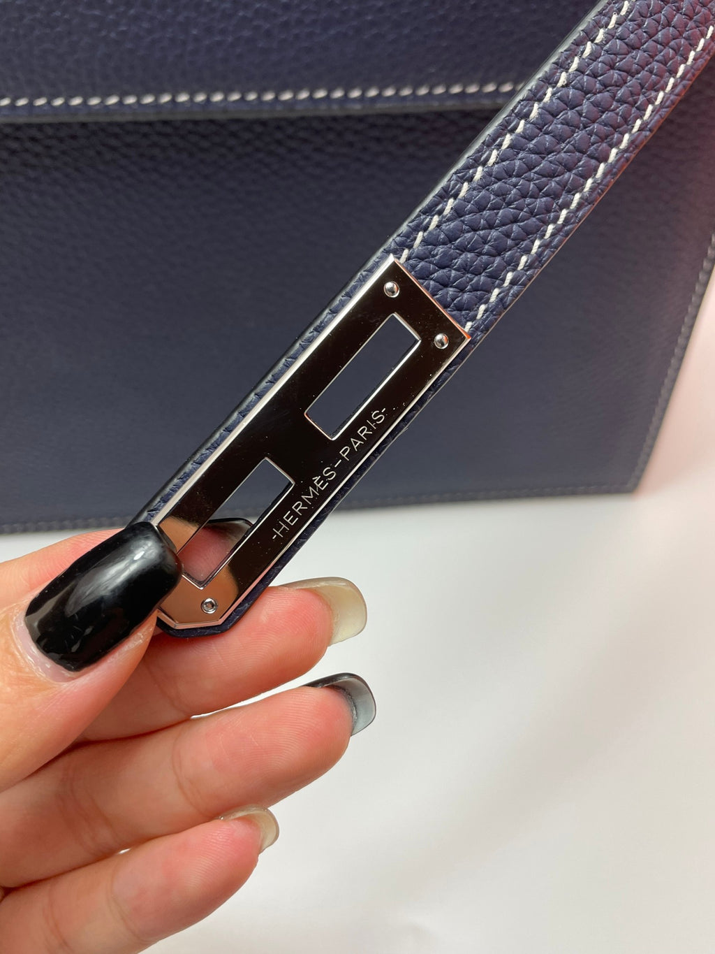 Leather strap with Hermes Paris engraved metal clasp on navy bag