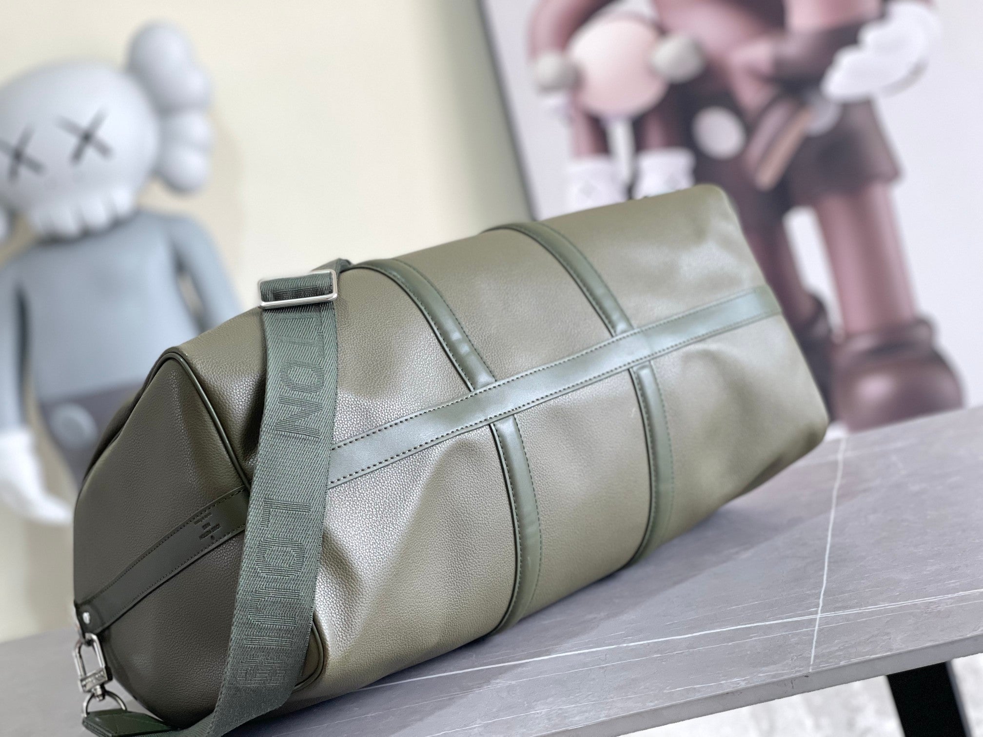 Olive green leather duffel bag with front flap and zipper top