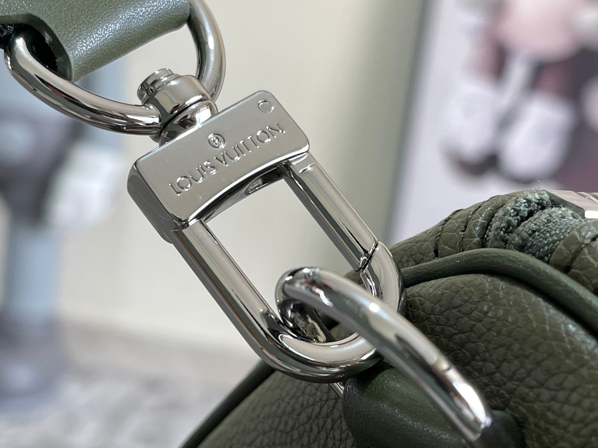 Men's Louis Vuitton duffel bag clasp close-up with silver-tone metal hardware