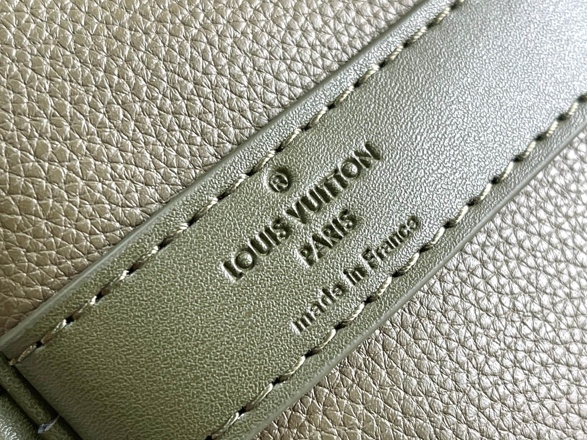 Men's Louis Vuitton leather tab detail with embossed logo on olive green duffel