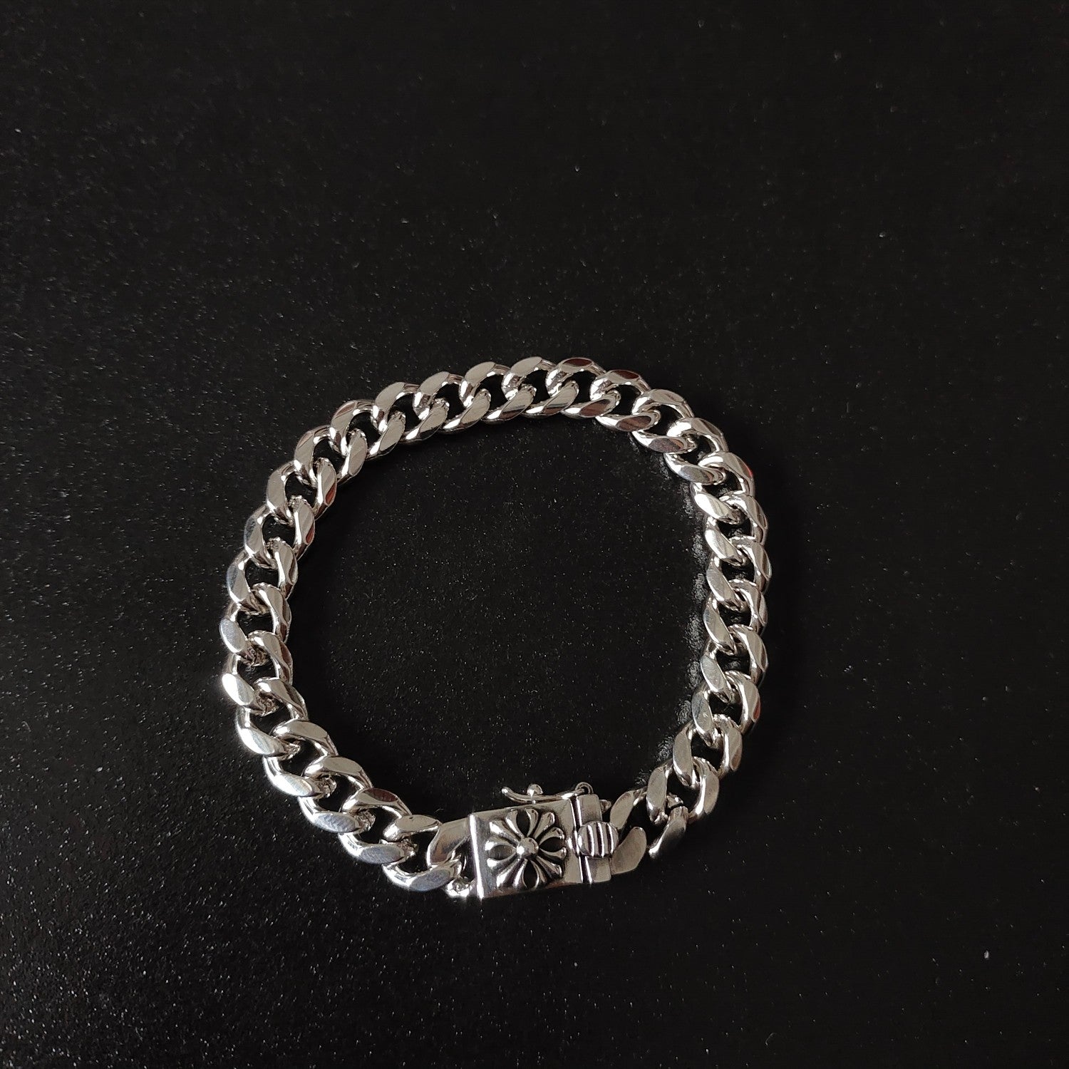 Silver chain bracelet with floral charm at center, chunky link chain