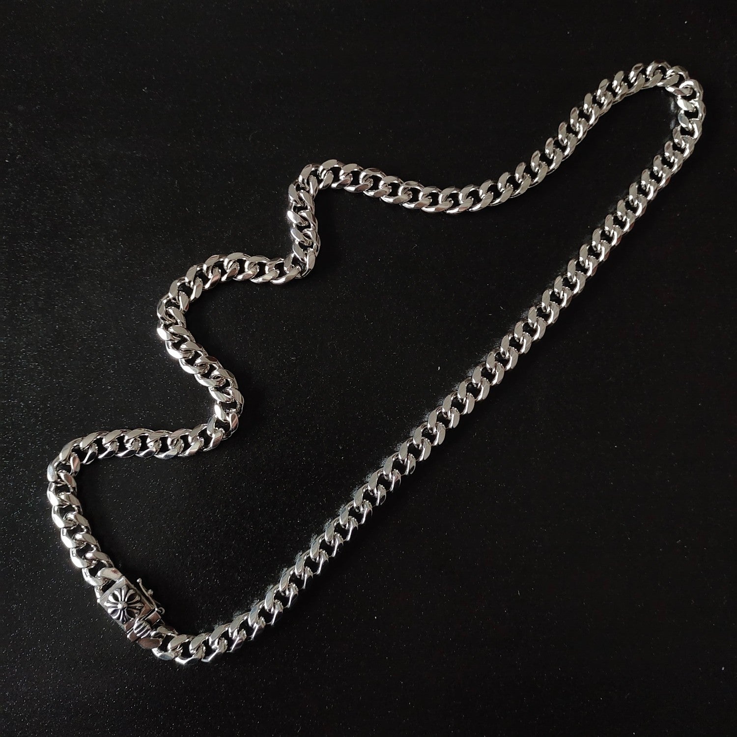Silver chain necklace with chunky links and small floral charm detail