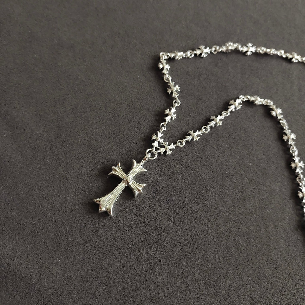 Silver cross pendant necklace with small star-flower chain links