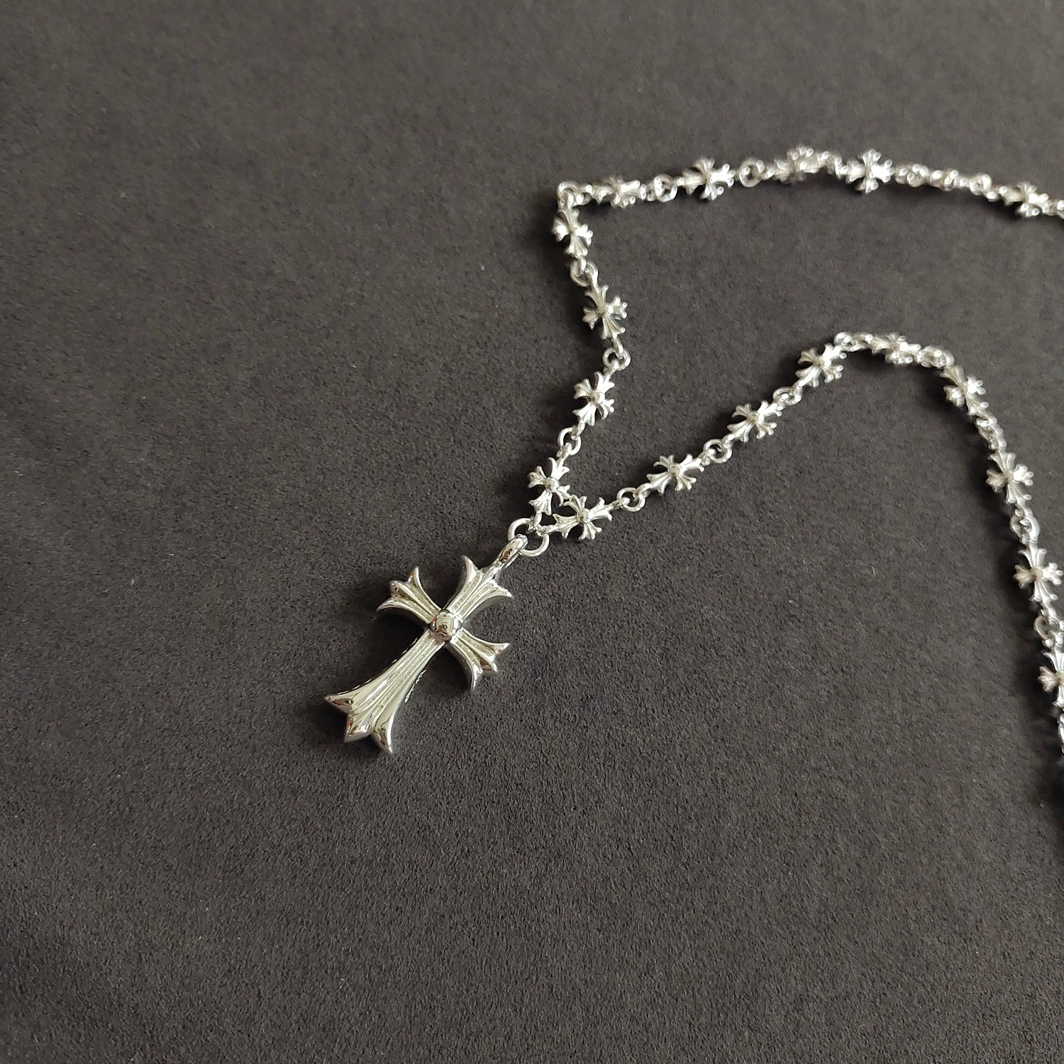 Silver cross pendant necklace with small star-flower chain links