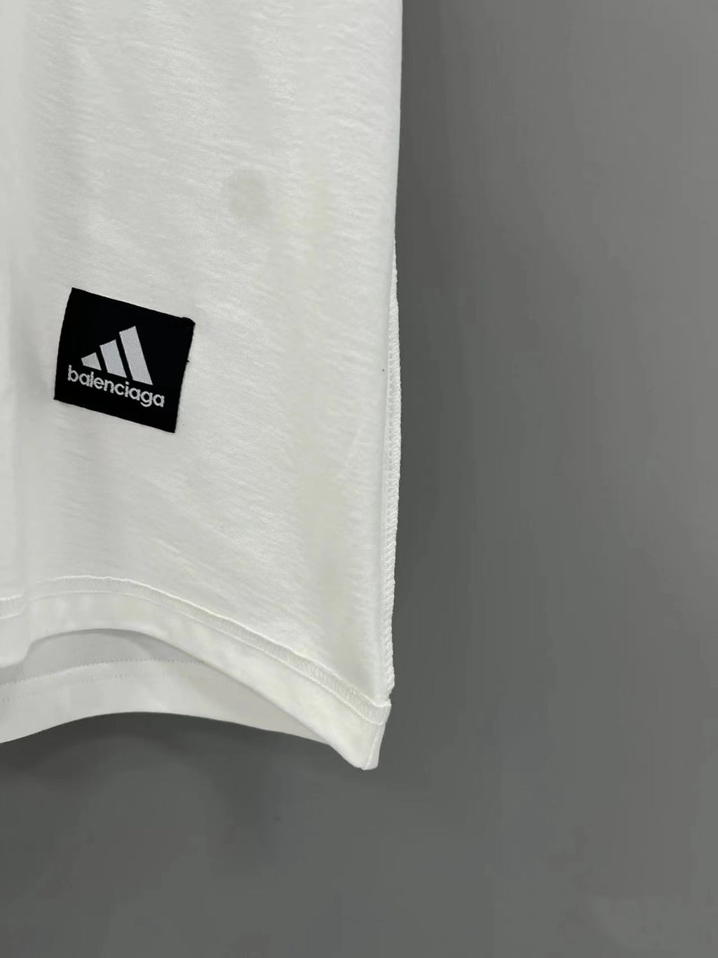 Close-up of white T-shirt hem with small Balenciaga logo patch