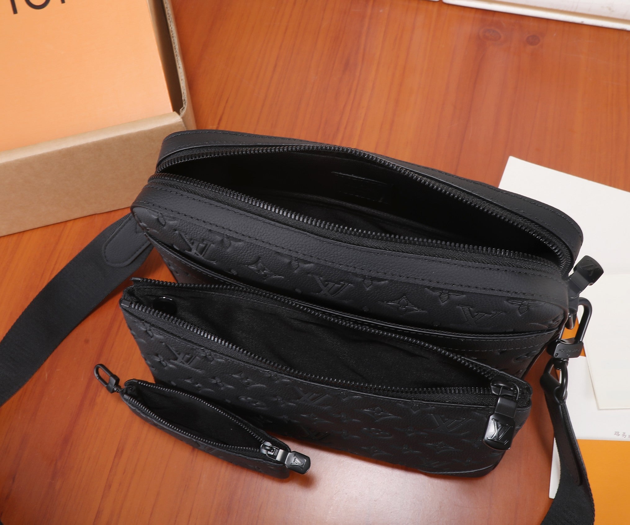 Men's crossbody bag with two zip compartments, black strap, embossed monogram exterior