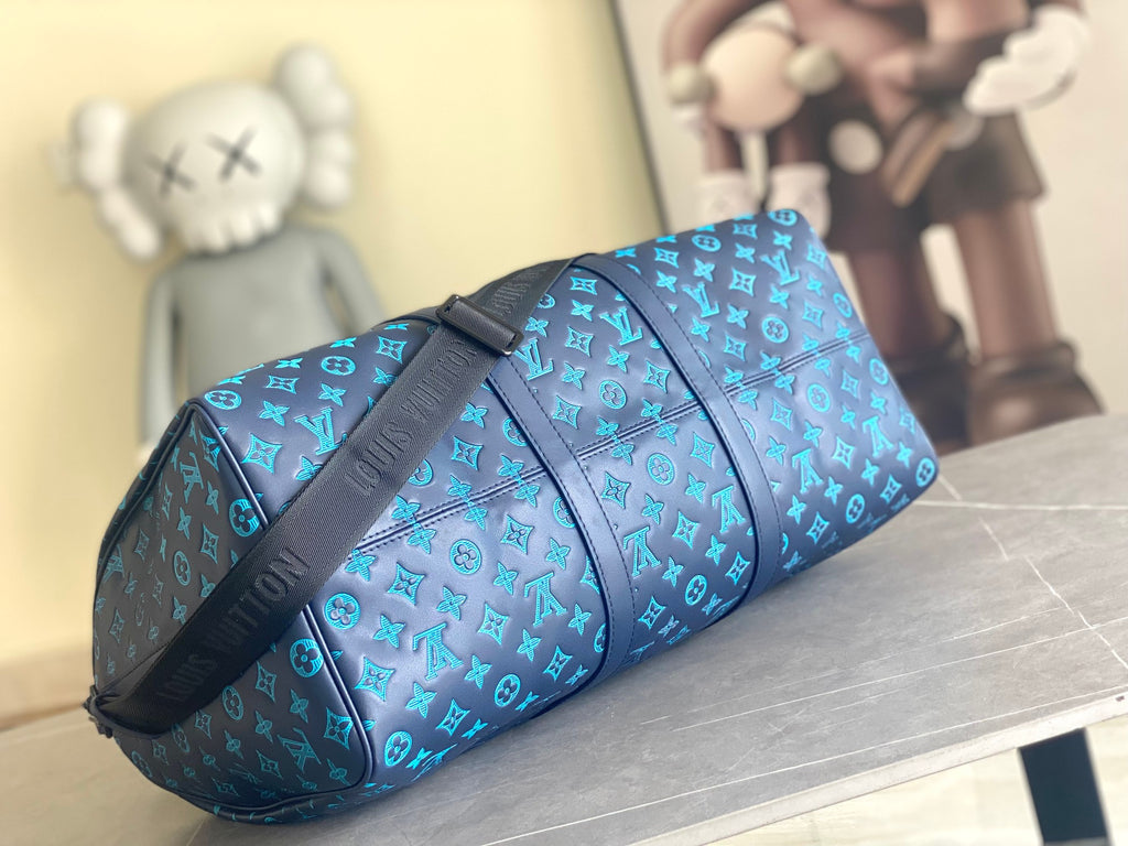 Teal monogram duffel bag with black strap and end view hardware