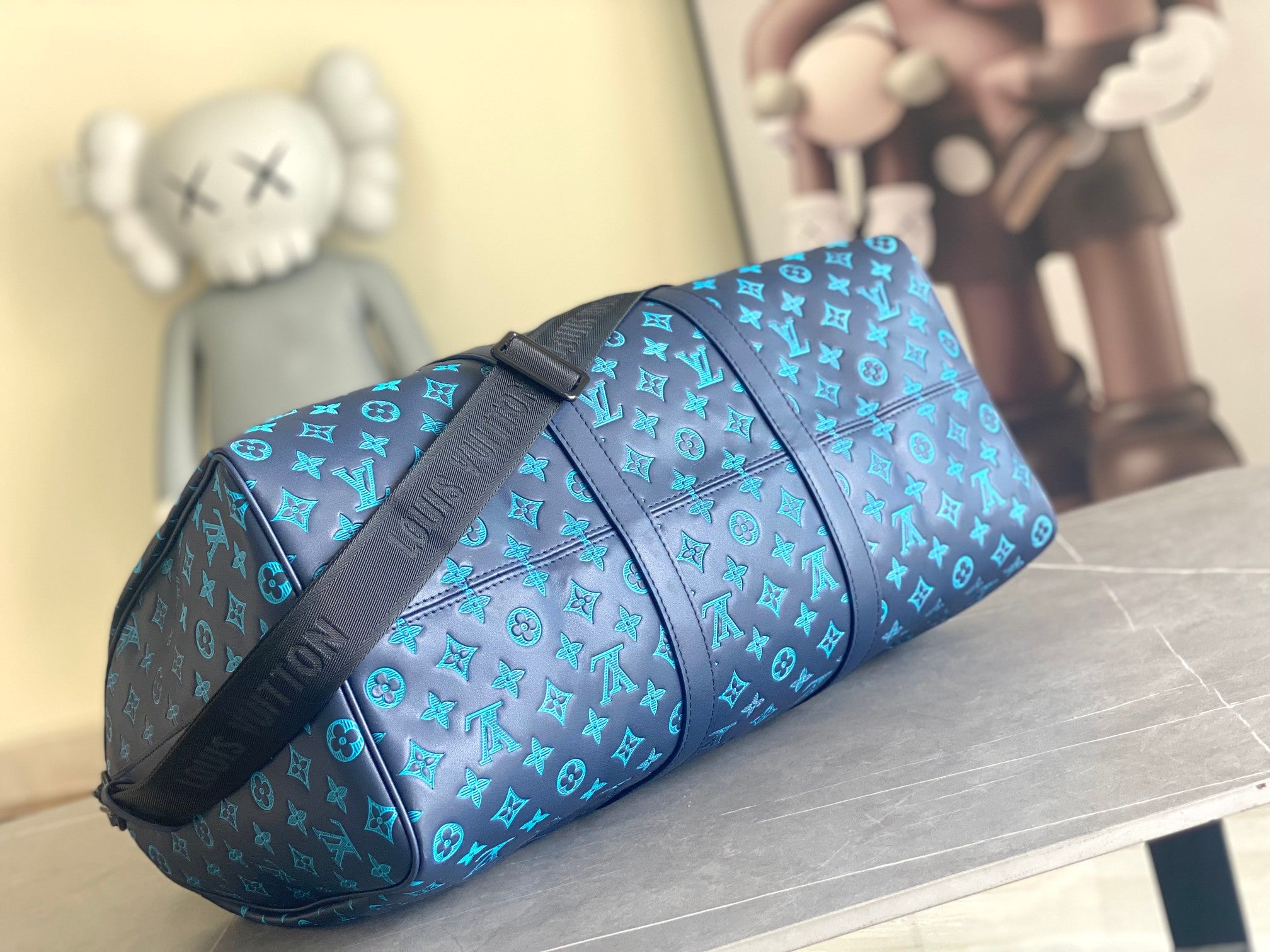 Teal monogram duffel bag with black strap and end view hardware