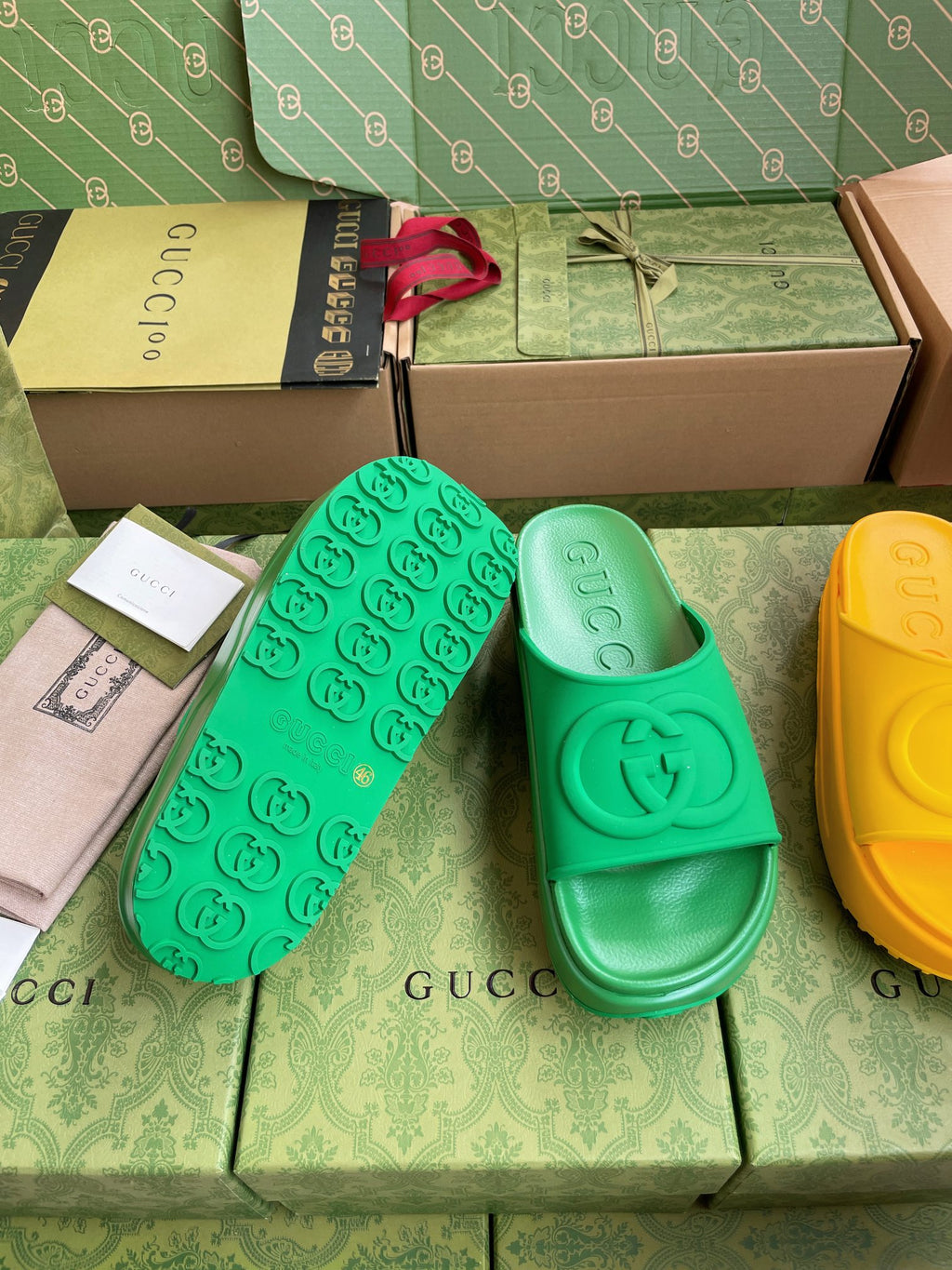 Gucci slide sandals in bright green with embossed logo footbed on display.
