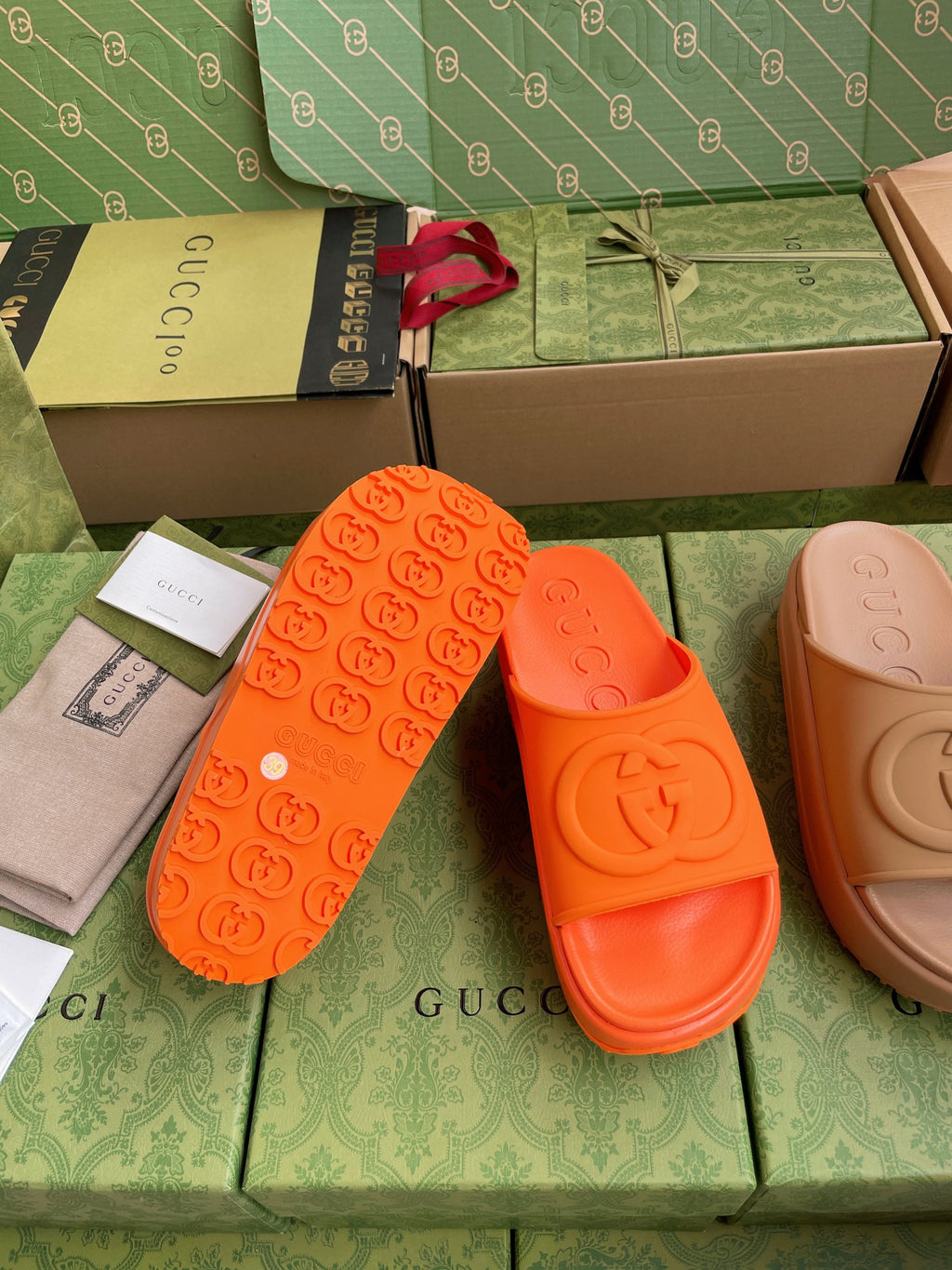 Gucci logo slide sandals, orange straps with embossed footbed and one side view