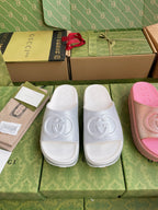 Logo slide sandals in white and pink, embossed emblem on wide foot straps